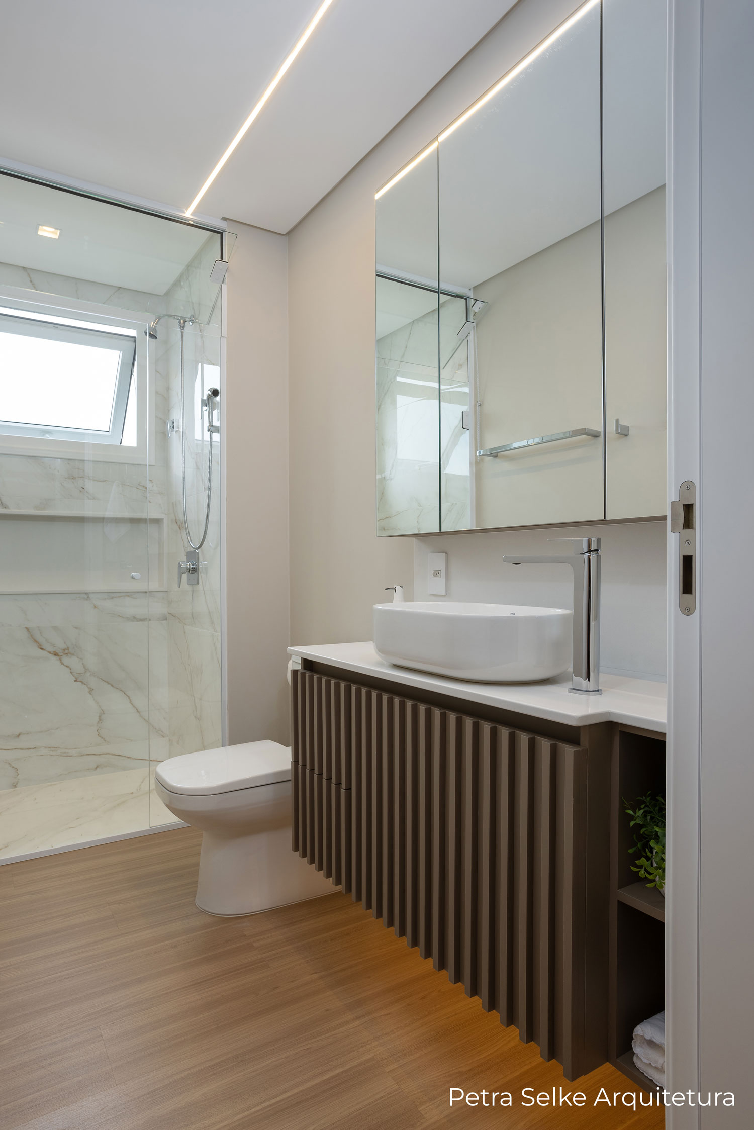 Banheiro aéreo com espelho e móvel com portas ripadas em MDF marrom